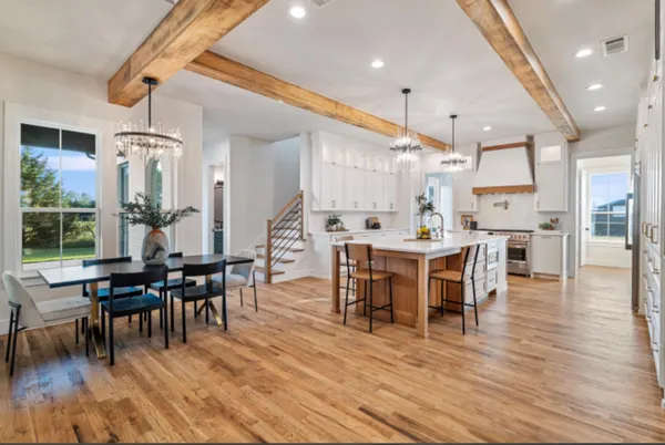 Great room with the dining table, the kitchen island and the stair under exposed beams