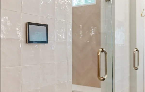 Glass shower door with brass handles and a digital shower control
