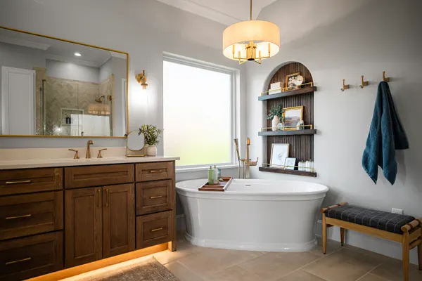 Primary bath with a dark wood vanity, a freestanding tub and an arched shelf niche