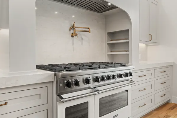 Professional-style range and pot filler in an arched alcove