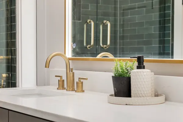 Brass faucet, with the green tile shower in the mirror