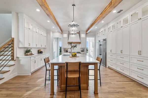 Kitchen with white cabinets to the ceiling, a chandelier over the island and the stair beside it
