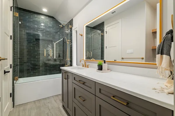 Bath with a deep green tile shower and a gray vanity