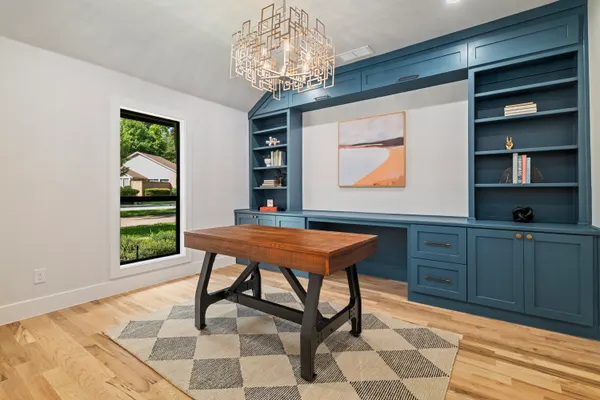 Office with navy built-in shelves and a wood desk