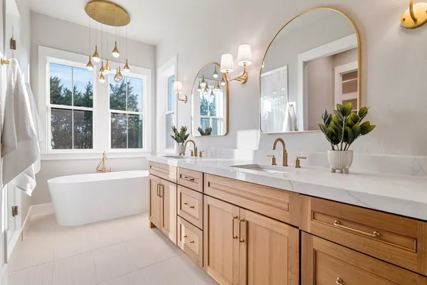 Primary bath with a freestanding tub, a white oak double vanity and brass arched mirrors