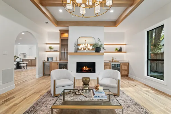 Fireplace between floating shelves, under a tray ceiling with a brass chandelier
