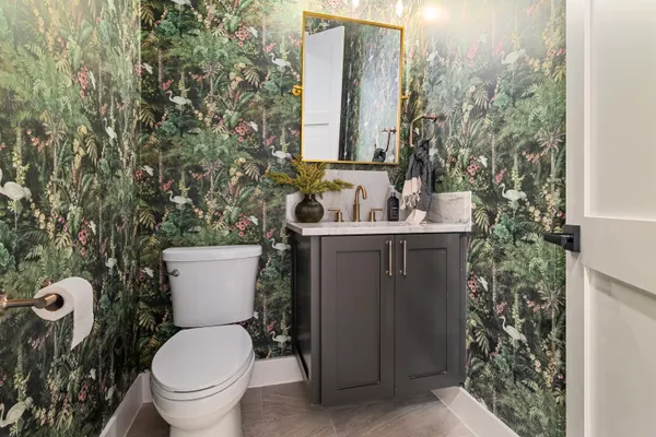 Powder room in botanical wallpaper, with a charcoal vanity