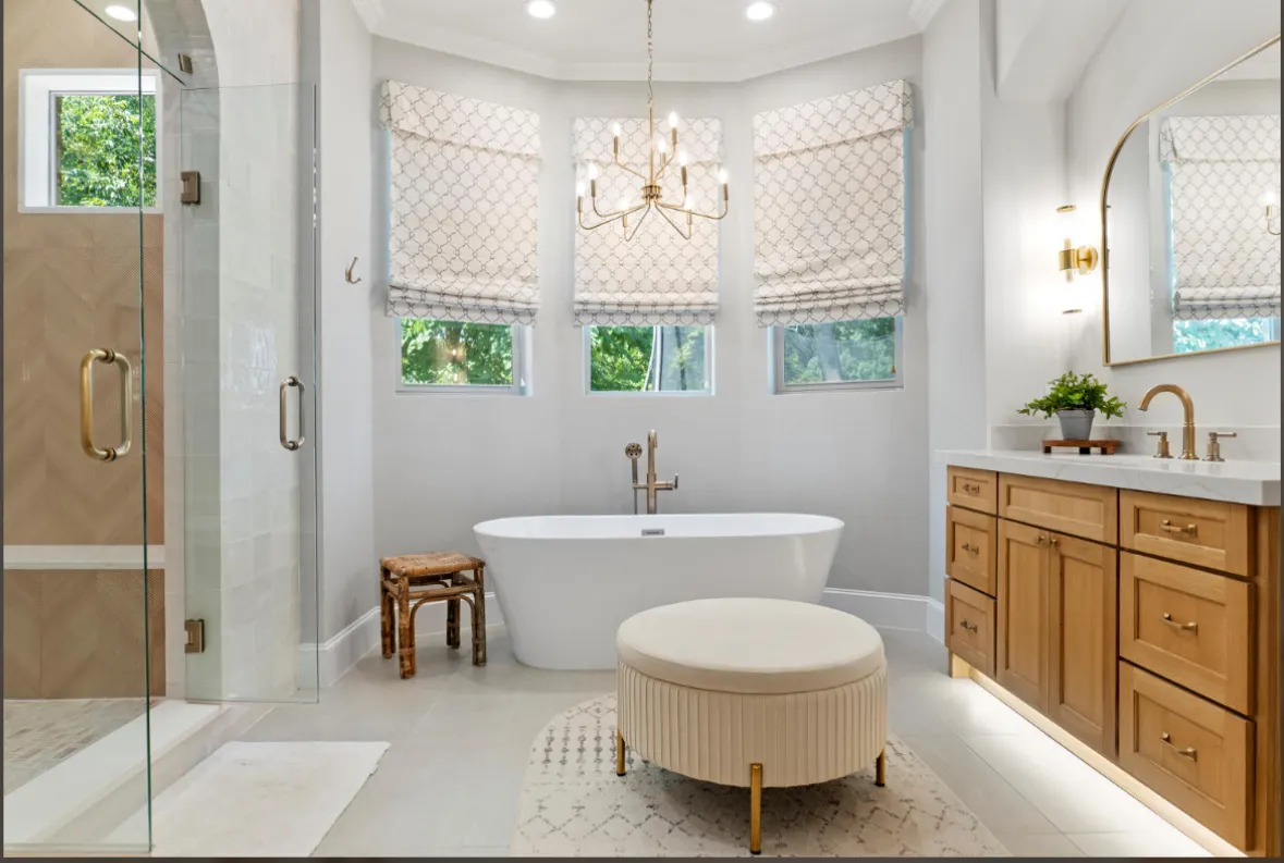 Primary bath with a freestanding tub in a bay window and a wood vanity