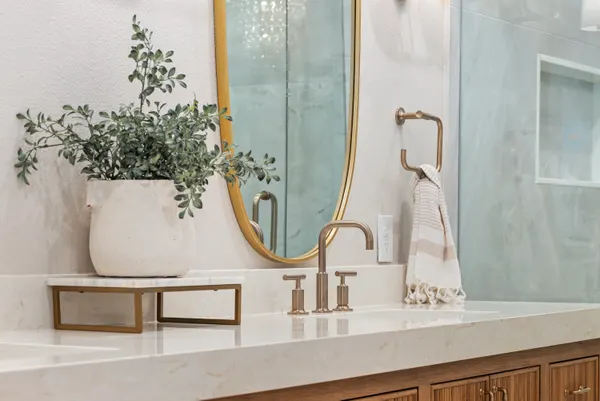 Brass faucet and an oval mirror at the primary vanity
