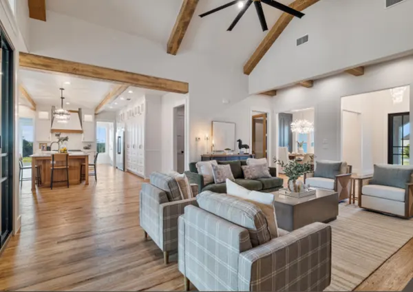 Living room under a beamed ceiling, open to the kitchen