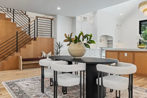 Round dining table in front of the stair, with the kitchen beyond