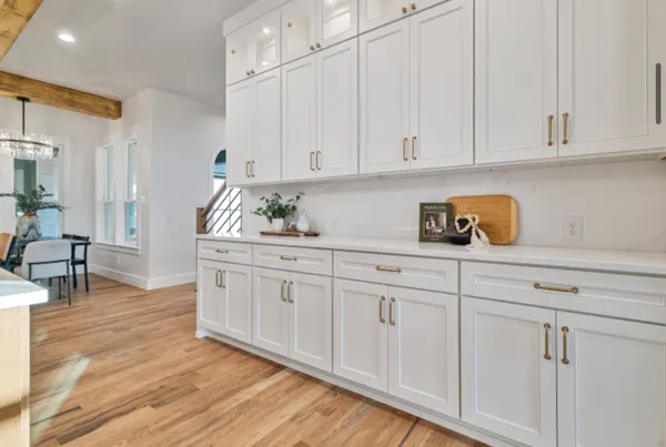 Wall of white cabinetry with glass-front uppers and brass pulls