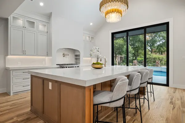 Kitchen island with seating, white cabinets and black-framed sliding doors to the pool