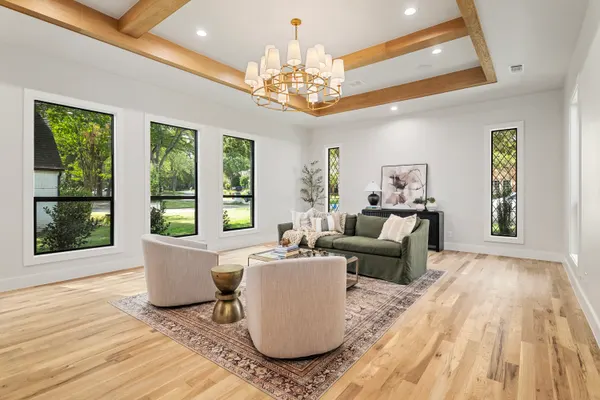 Living room under a wood-trimmed tray ceiling with a chandelier