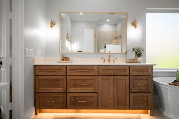 Wood vanity lit from below, with a brass framed mirror