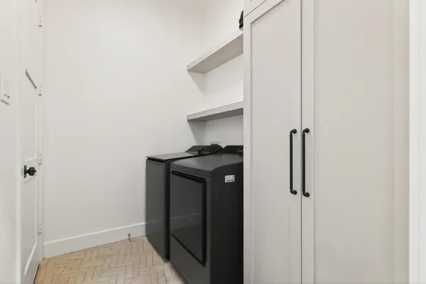 Laundry room with a tall white cabinet, open shelves and a herringbone tile floor