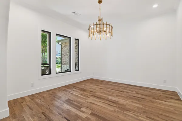 Room with a gold chandelier and black-framed windows