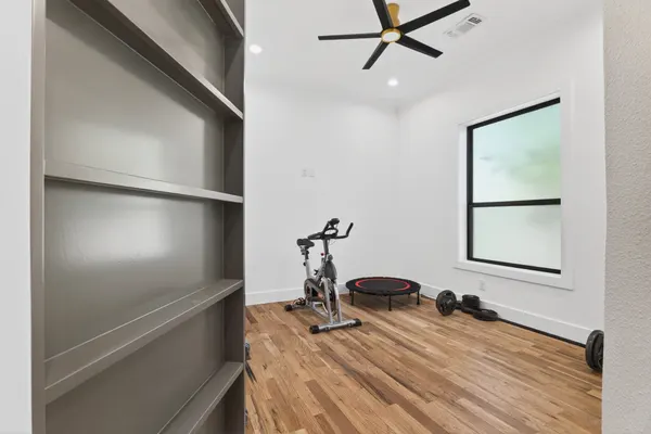 Exercise room with a black-framed window, beside gray built-in shelves