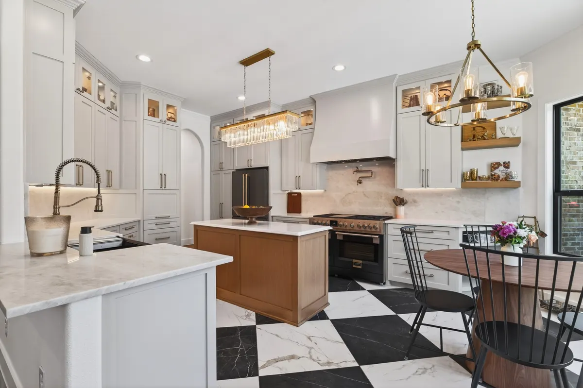 Kitchen with a wood island, white cabinets to the ceiling and a black and white checkerboard floor