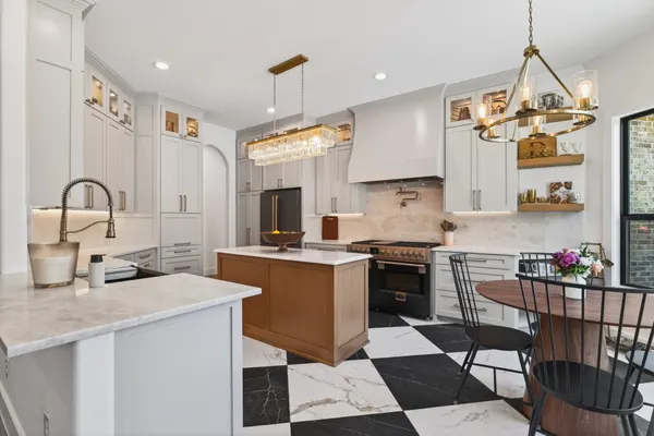 Kitchen with a wood island, white cabinets to the ceiling and a black and white checkerboard floor