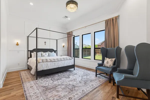 Primary bedroom with paneled walls and black-framed windows