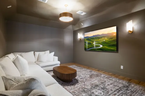 Media room with a sectional facing a wall-mounted TV, under a drum pendant