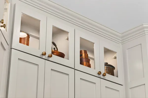 Glass-front upper cabinets, lit inside, under crown molding