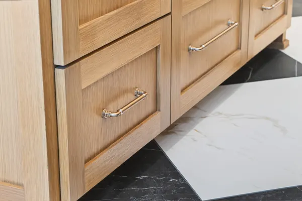 Wood island drawers with brass pulls over the checkerboard floor