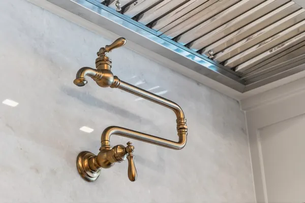 Brass pot filler on the slab backsplash under the range hood