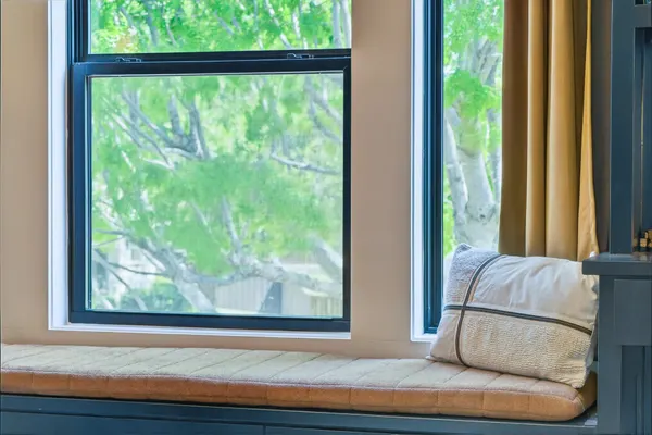 Window seat with drawers under a black-framed window, between built-in shelves