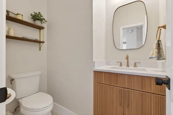 Powder room with a fluted wood vanity, a brass faucet and wood shelves on brass brackets
