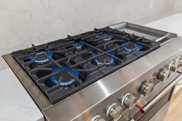 Gas burners lit on the professional-style range, against the slab backsplash