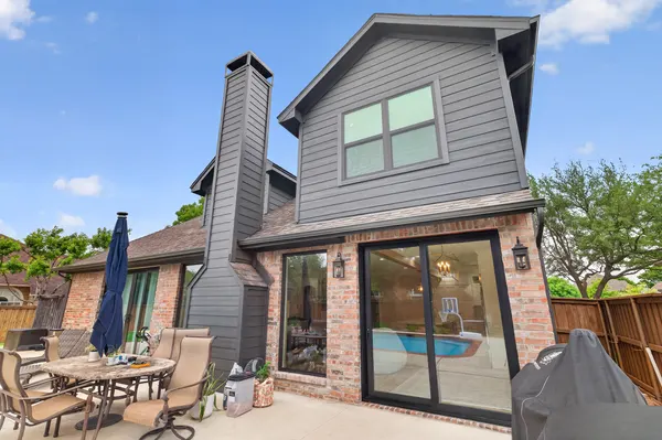 Back of the house, with gray siding above the brick and black-framed sliding doors to the patio