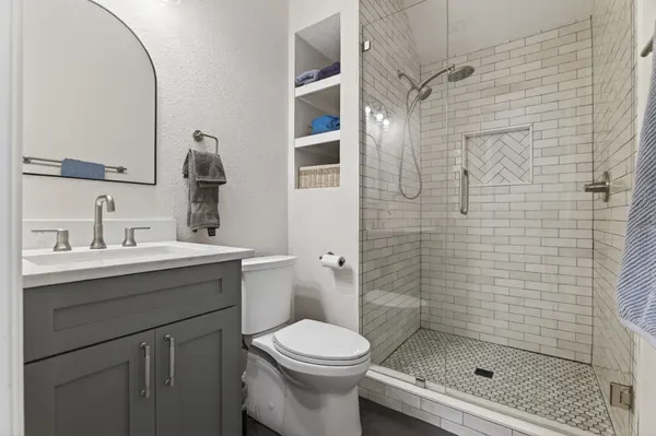 Bath with a gray vanity and a glass shower in white subway tile with a herringbone niche