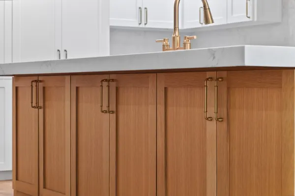 Wood island cabinets with brass pulls under the thick white countertop