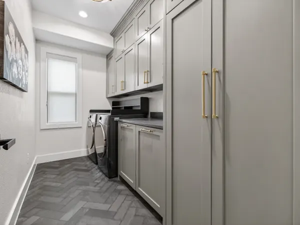 Laundry room with gray cabinets to the ceiling and a herringbone tile floor