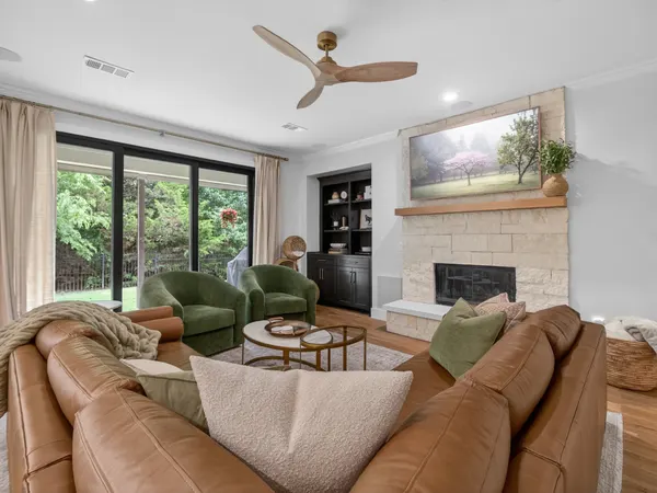 Living room with a stone fireplace and a wall of black-framed sliding doors