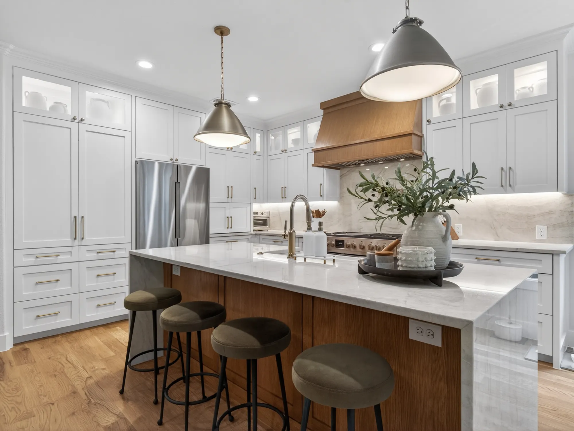 Kitchen with white cabinets to the ceiling, a wood range hood and a wood island with a waterfall top