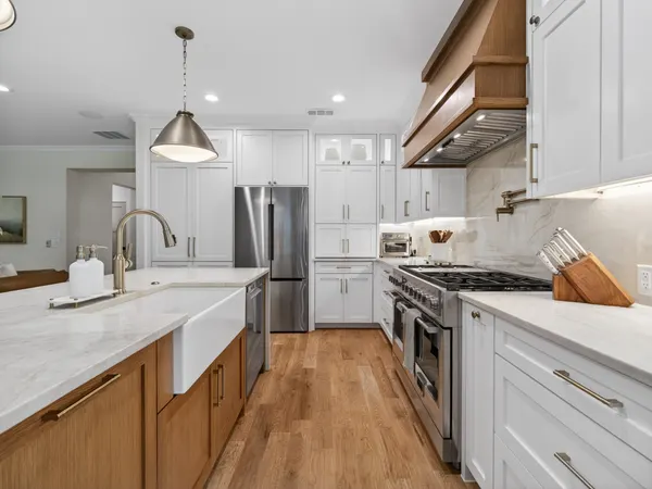 Farmhouse sink and brass faucet in the island, with the range and the refrigerator wall beyond