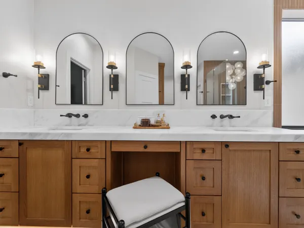 Double vanity with a seated makeup space between the sinks, under three arched mirrors