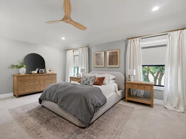 Bedroom with a wood-blade ceiling fan and windows on two walls