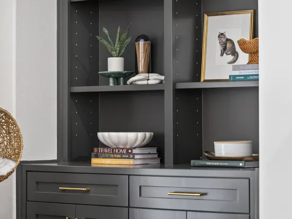 Charcoal built-in shelves and cabinets with brass pulls