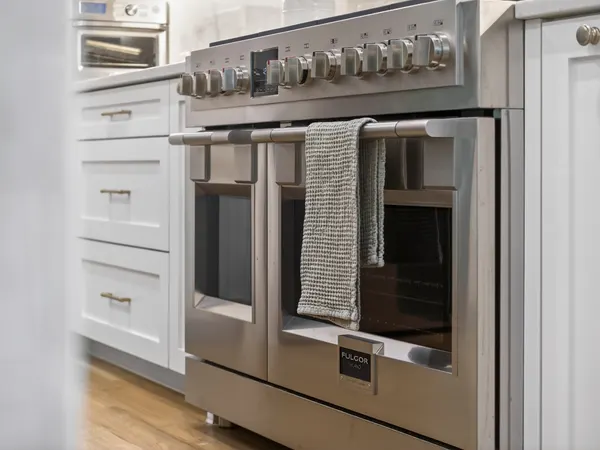 Professional-style range with double ovens beside white drawers