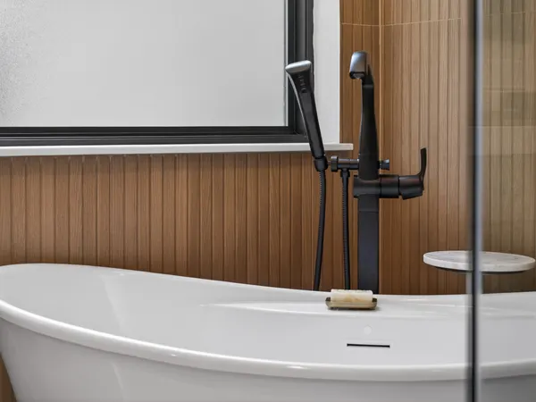 Matte black floor-mounted tub filler at the freestanding tub