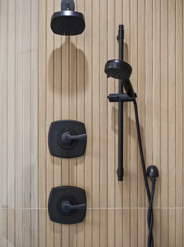 Matte black showerhead, controls and handheld shower on fluted wood-look tile