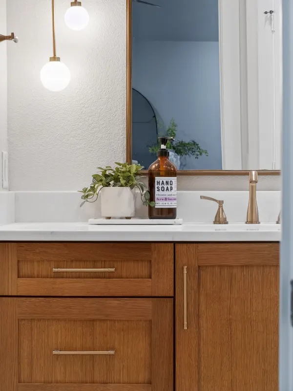 Wood vanity with brass pulls and a brass faucet